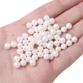 Loose white half-hole imitation pearls for DIY jewelry making held in a palm - 2 Pieces/Pack / Approx. 6mm (1mm Hole) / White
