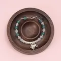 Ethnic style beaded bracelet with silver butterfly pendant on a pine wood tray display - Walnut Round Tray