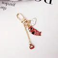 Detailansicht des goldenen Koi-Schlüsselanhängers mit Daruma-Anhänger und Karabiner - Roter Koi