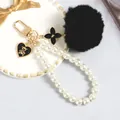 Dettaglio portachiavi pompon nero con catena di perle e ciondolo a forma di orsetto - Nero