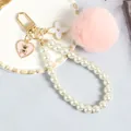 Dettaglio di ciondolo orso con pompon rosa, anello di perle e portachiavi a fiori - Rosa
