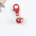Detail of a red heart-shaped lobster clasp with an iridescent resin heart pendant - Red