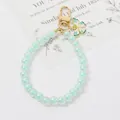 Dettaglio del portachiavi con perle color menta e ciondolo a farfalla smaltato su sfondo bianco - Azzurro/Verde Menta (5106-1)