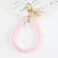 Dettaglio del portachiavi con perle rosa iridescenti, ciondolo a farfalla dorata e chiusura - Rosso Rosa (5106-4)