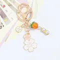 Detail of keychain featuring gold peanut charms, orange persimmon bead and sakura flowers - Double Flower H Round Plate Persimmon Peanut Style (5133-2)