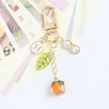 Detail of golden keychain with persimmon, peanut charm, and pearl on white cards - Green Leaf H Round Plate Persimmon Peanut Style (5133-3)