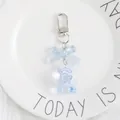 Close-up of a light blue crystal bear keychain with a bow on a white plush background - Blue