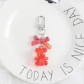 Detailed macro view of a red crystal bear keychain with a purple metallic bow - Red