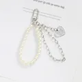 Dettaglio del portachiavi a doppia catena in metallo con perle bianche e ciondolo a cuore - Stile Cuore Inciso e Perla (5165-1)