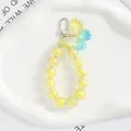 Dettaglio di ciondolo a farfalla con perline gialle iridescenti su vassoio bianco - Sfumato Giallo-Blu (5164-2)