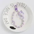 Dettaglio del portachiavi con perline viola a cuore e fiocco su un vassoio di ceramica - Viola