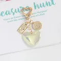 Detail of vintage heart keychain with gold coin pendant and iridescent green heart charm - AB White