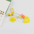 Détail d'un porte-clés tournesol en acrylique jaune avec clochette et pendentif coeur - Jaune