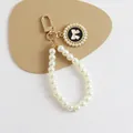 Detailed macro view of white faux pearl keychain with golden clasp and bow pendant - Black Base White Bow Style (5182-3)