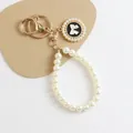 Detail of elegant pearl keychain with a black and white bow charm and golden hardware - Black Enamel Bow Style (5182-4)