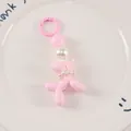 Detail of pink balloon dog keychain with white pearl collar on decorative white plate - Rose Red