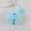 Close-up of blue plush monster keychain with colorful smile beads and heart charm - Light Blue