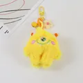 Detail eines gelben Plüsch-Monster-Schlüsselanhängers mit Stickerei und Blumenanhänger - Gelb