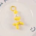 Detail of bright yellow balloon dog keychain with large pearl accent on white tray - Yellow