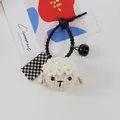 Handmade crochet sheep hair tie with black bell and checkered tag on gray background - Sheep Hair Ornament And Checkerboard Square Tag (5194-1)