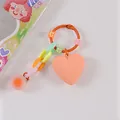 Dettaglio di un portachiavi a cuore colorato con perline smiley e cuore in acrilico arancio - Arancione (8189-7)