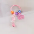 Détail du porte-clés rose Y2K avec cœur scintillant, perles de lettres et petit grelot - Rose