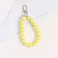 Detailed macro view of yellow acrylic bead charm with glossy silver lobster clasp and key ring - Yellow