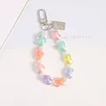 Macro detail of iridescent heart beads and silver embossed metal tag on a sweet keychain - Multicolor