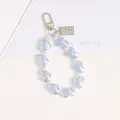 Detailed macro view of heart-shaped iridescent blue beads and white faux pearls on key chain - Blue