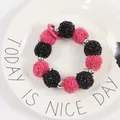 Detalle de pulsera de pompones rosa y negro con hilos dorados y cuentas de plata en un plato - Estilo Pompon Contraste Rosa Fuerte Negro (yc5213-玫+黑)