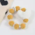 Porte-clés cœur en peluche avec pompons jaunes et perles nacrées en gros plan - Jaune