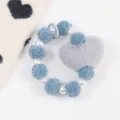 Dettaglio del cinturino in peluche con palline blu, perle bianche e ciondolo a cuore grigio - Blu