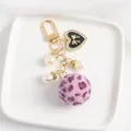Close-up of heart charm with crystals, pearls, and pink leopard print faux fur pompom - Pink Leopard