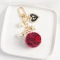 Close-up of leopard print faux fur ball keychain with heart pendant and pearls - Red Leopard
