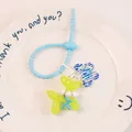 Macro shot of yellow translucent balloon dog keychain with floral pendant on a ceramic plate - Green