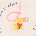 Macro shot of yellow resin balloon dog keychain with pink flower charm on ceramic plate - Yellow