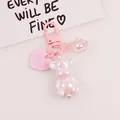 Detailed macro view of pink pearlescent bear keychain with heart and flower charms - Soft Pink