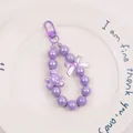 Macro shot of purple beaded keychain with a cute bear pendant and iridescent bow - Purple