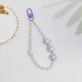 Detailed macro of sweet purple flower charms and pearl beads on a mobile phone strap - Purple