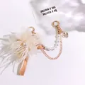 Macro detail of elegant feather keychain with pearl accent and gold metal chain - Champagne