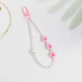 Close-up of pink floral keychain with pearl beads and shadow on white background - Pink