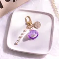 Dettaglio di un portachiavi a conchiglia viola con perle bianche e moschettone dorato - Viola