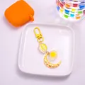 Detailed close-up of cartoon cloud and moon keychain with yellow resin ball and golden clasp - Yellow