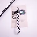 Close-up of checkerboard lanyard keychain with black bell and white daisy floral charm - Yc5305-4