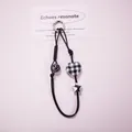Macro shot of phone lanyard detail with checkered heart bead and silver star charm - Black