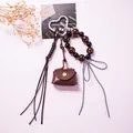 Detail of leather mini pouch keychain with leopard beads, heart clasp, and woven tassel - Camel