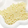 Perles ABS beiges rondes pour création de bijoux DIY dans un plat en céramique blanc - Light jaune
