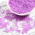 Bulk 2mm translucent bright purple glass seed beads in a white ceramic dish - Violet