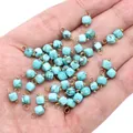 Faceted 4mm blue natural stone cube charms with gold rings held in palm for scale - Blue Sandstone