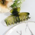 Close-up of a large olive green transparent hair claw clip with cross-teeth design - Green